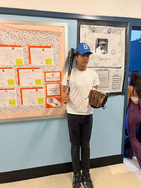 Student dressed as a baseball player with bat and glove for the Living Wax Museum