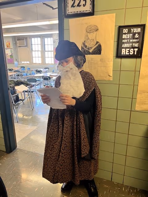 Student dressed as a historical figure in a robe and hat reading a speech for the Living Wax Museum