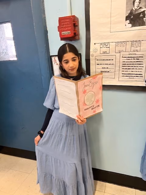 Student in a long dress reading her presentation at the Living Wax Museum