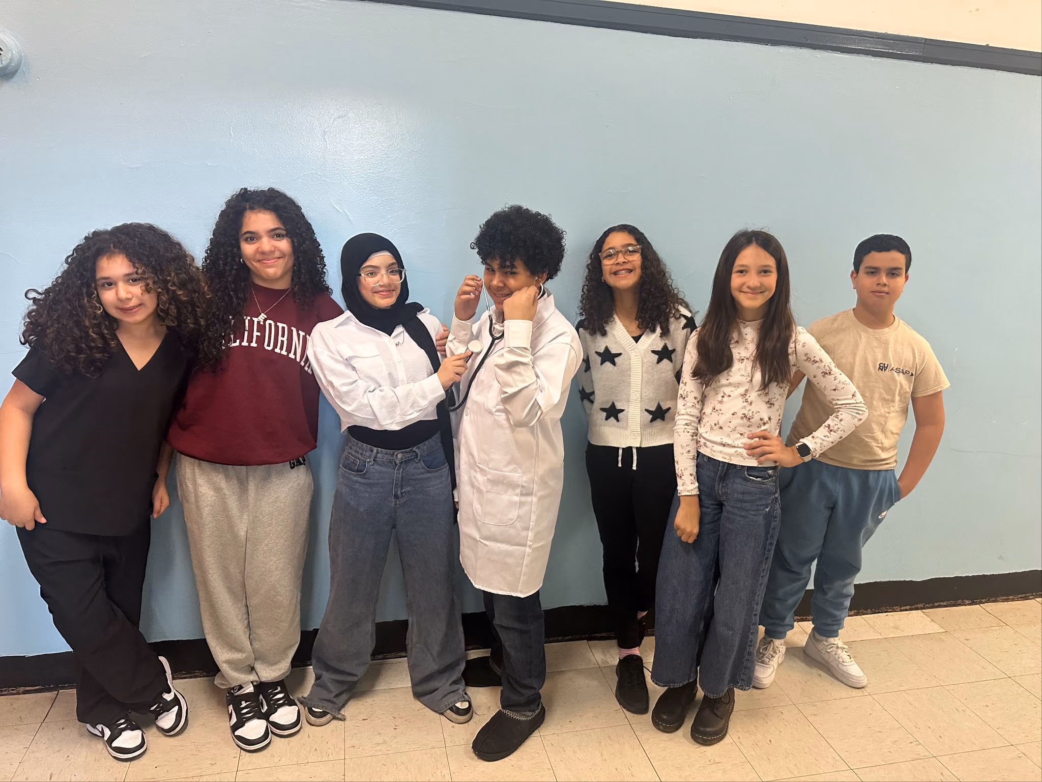 Students in college sweatshirts, scrubs and a lab coat on Career Day