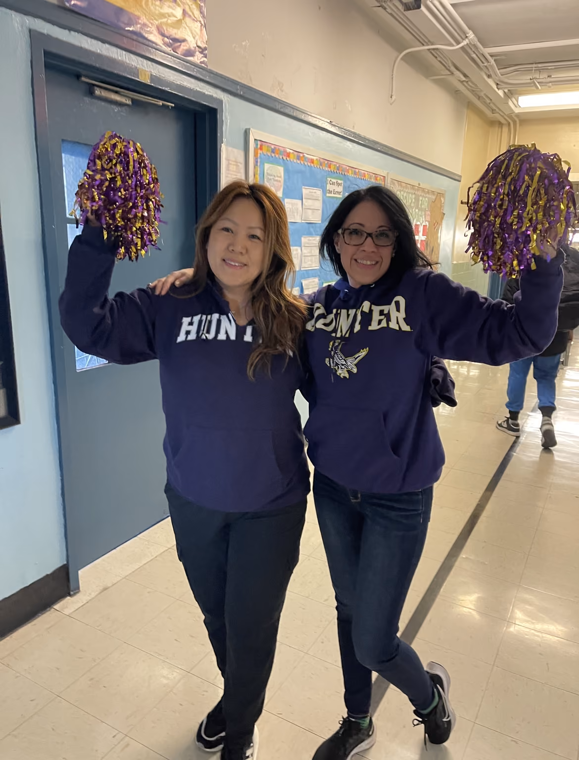 Two teachers in Hunter College sweatshirts holding pom-poms on Career Day