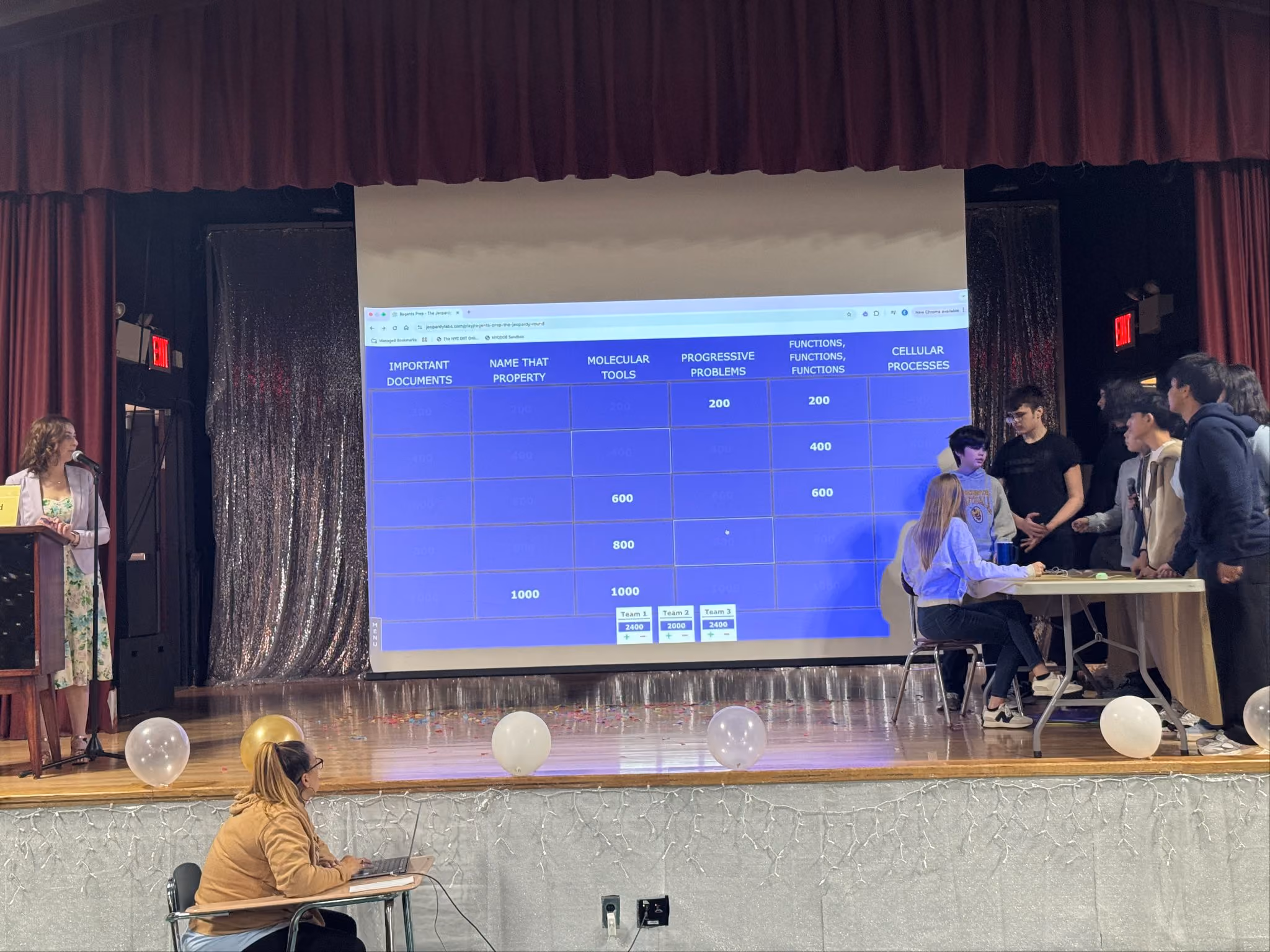 Jeopardy game board on the auditorium screen as student teams compete