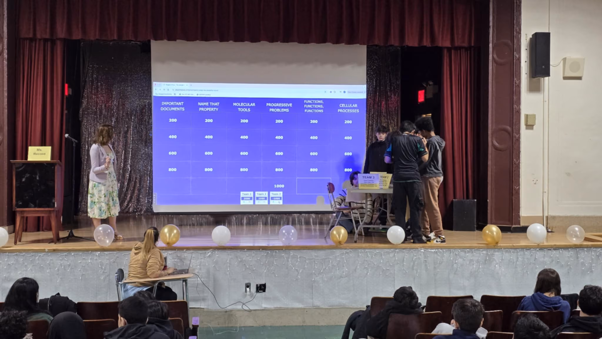 Student teams on the auditorium stage during MAA and RBG Jeopardy