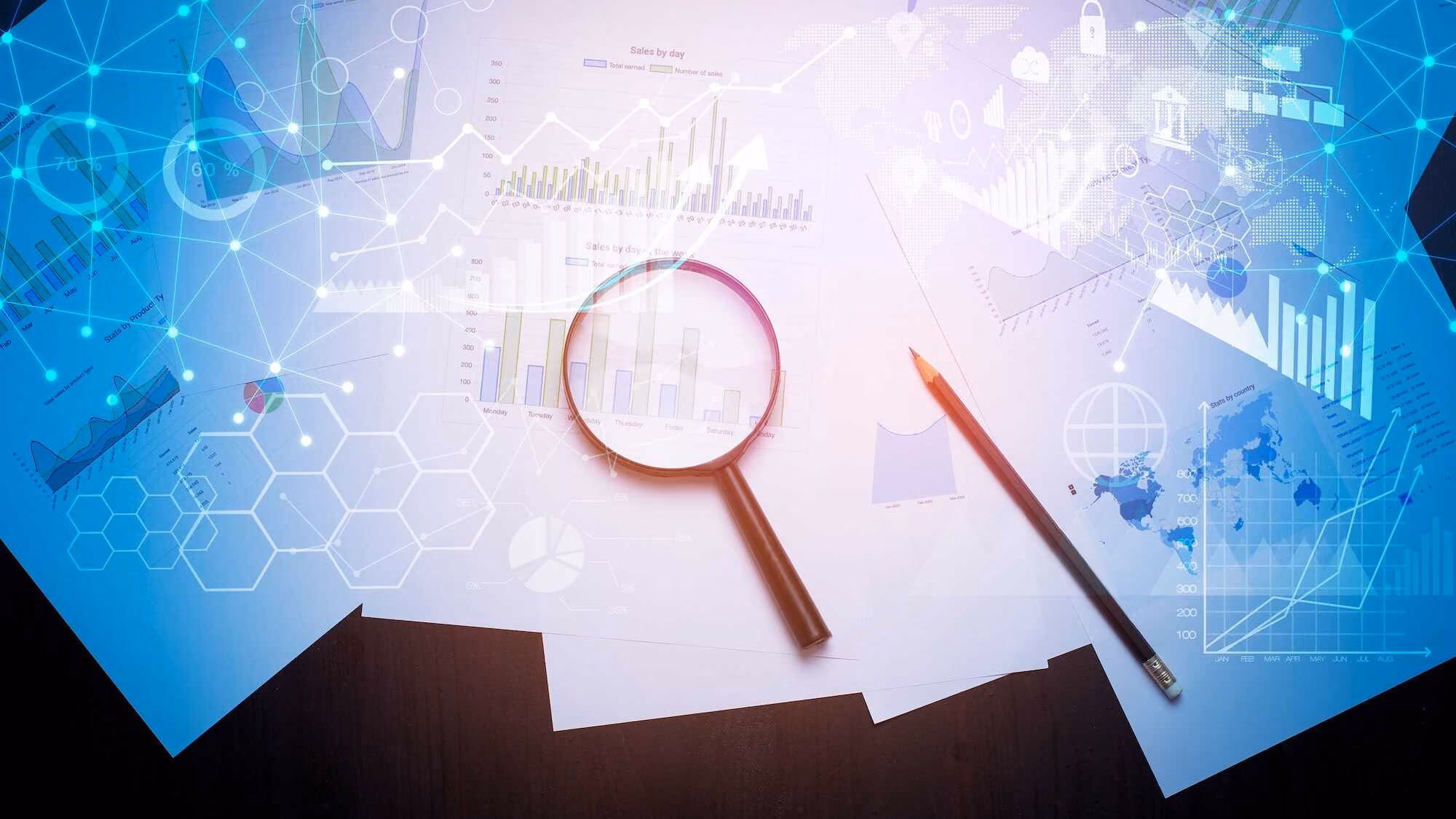 Magnifying glass and pencil on papers with various business charts and graphs, overlaid with digital network and data visualization graphics.