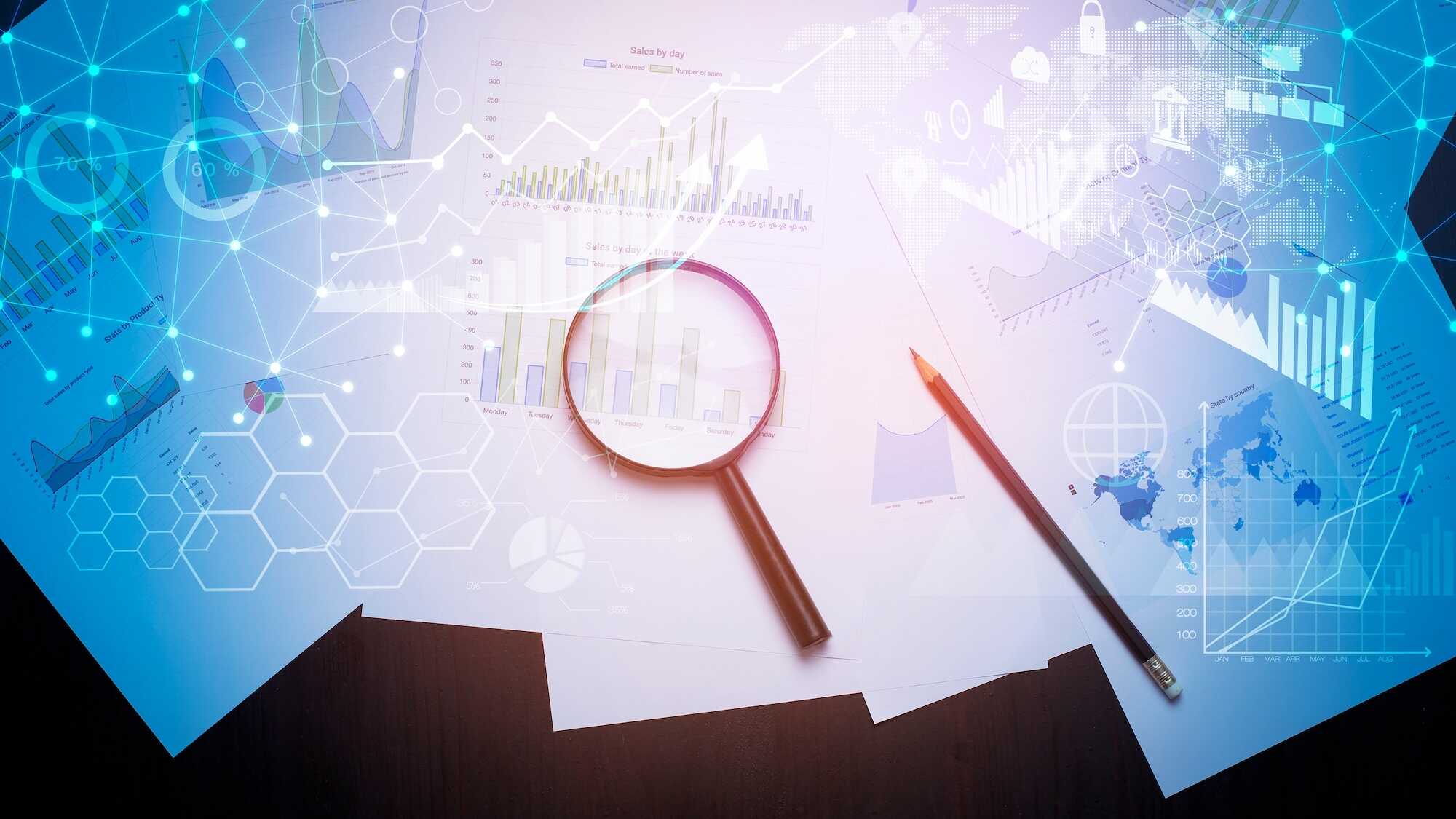 Magnifying glass and pencil on papers with various business charts and graphs, overlaid with digital network and data visualization graphics.