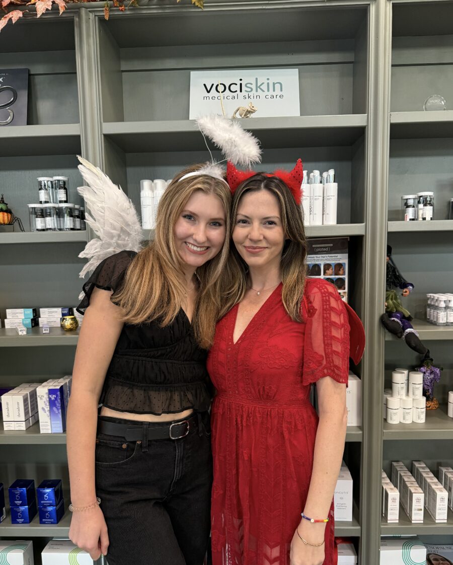 Two guests in angel and devil costumes by the VociSkin shelf
