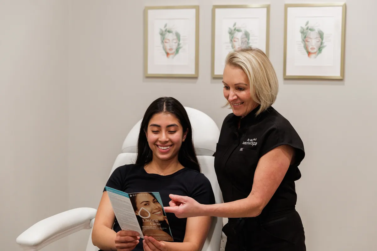 Dr. Gina Voci walking a smiling client through a treatment brochure