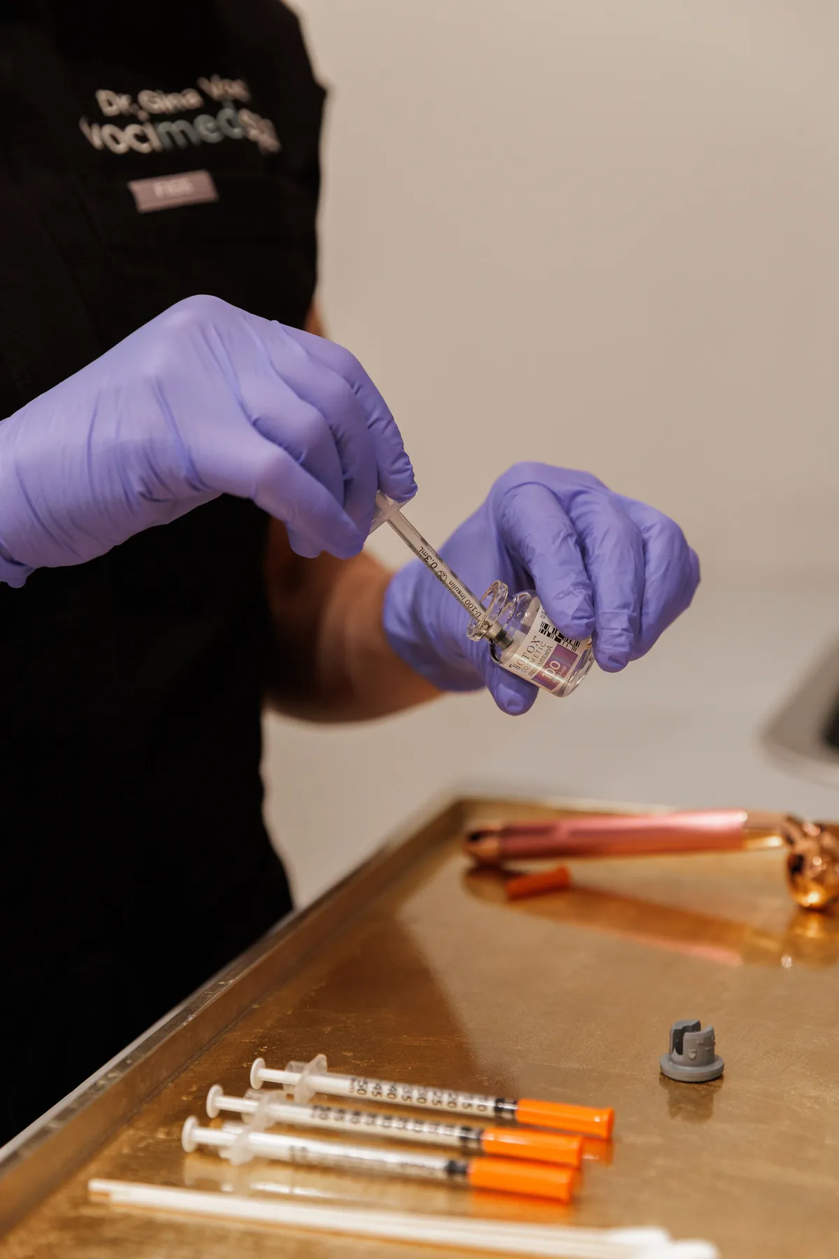 Gloved provider drawing Botox Cosmetic from a vial into a syringe