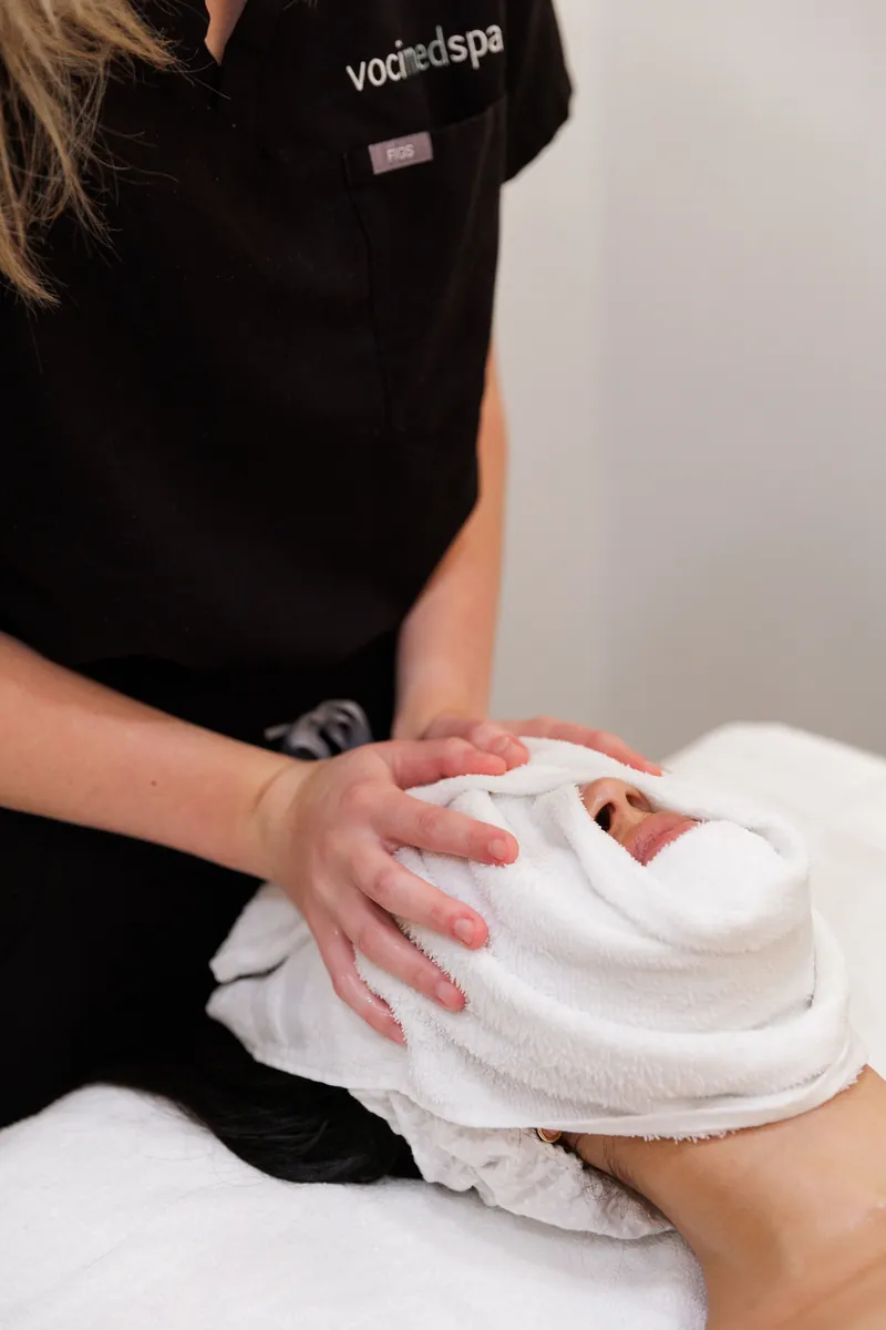 Esthetician applying a warm towel during a facial