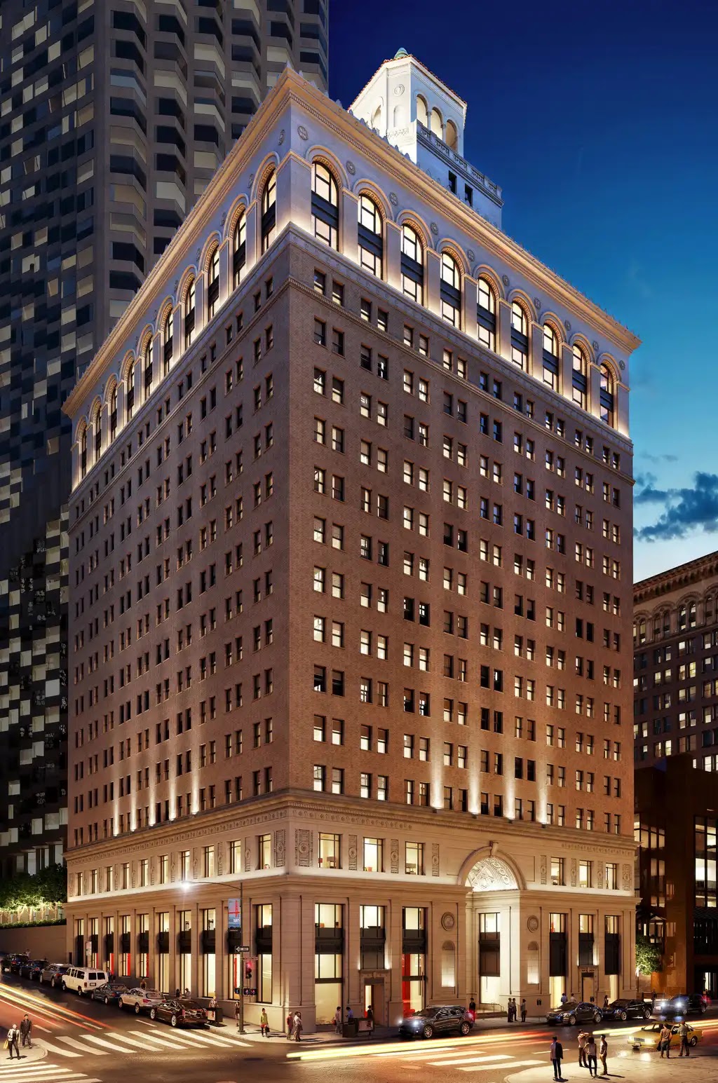 Historic building exterior illuminated at dusk with a city skyline in the background.