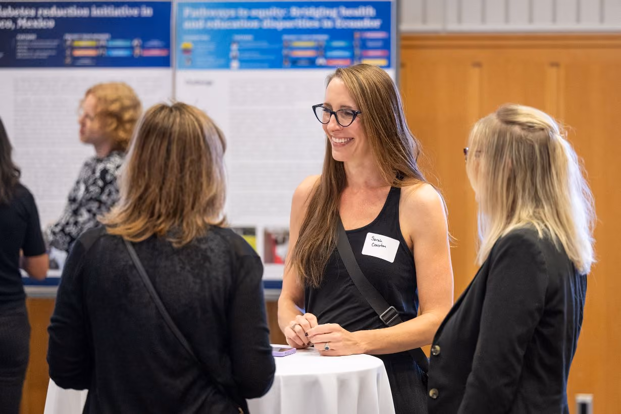 Three women connecting over high table at University of Michigan