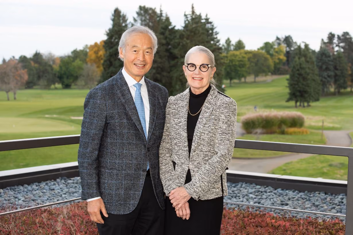 Founder Tachi Yamada and wife posing in front of grass field