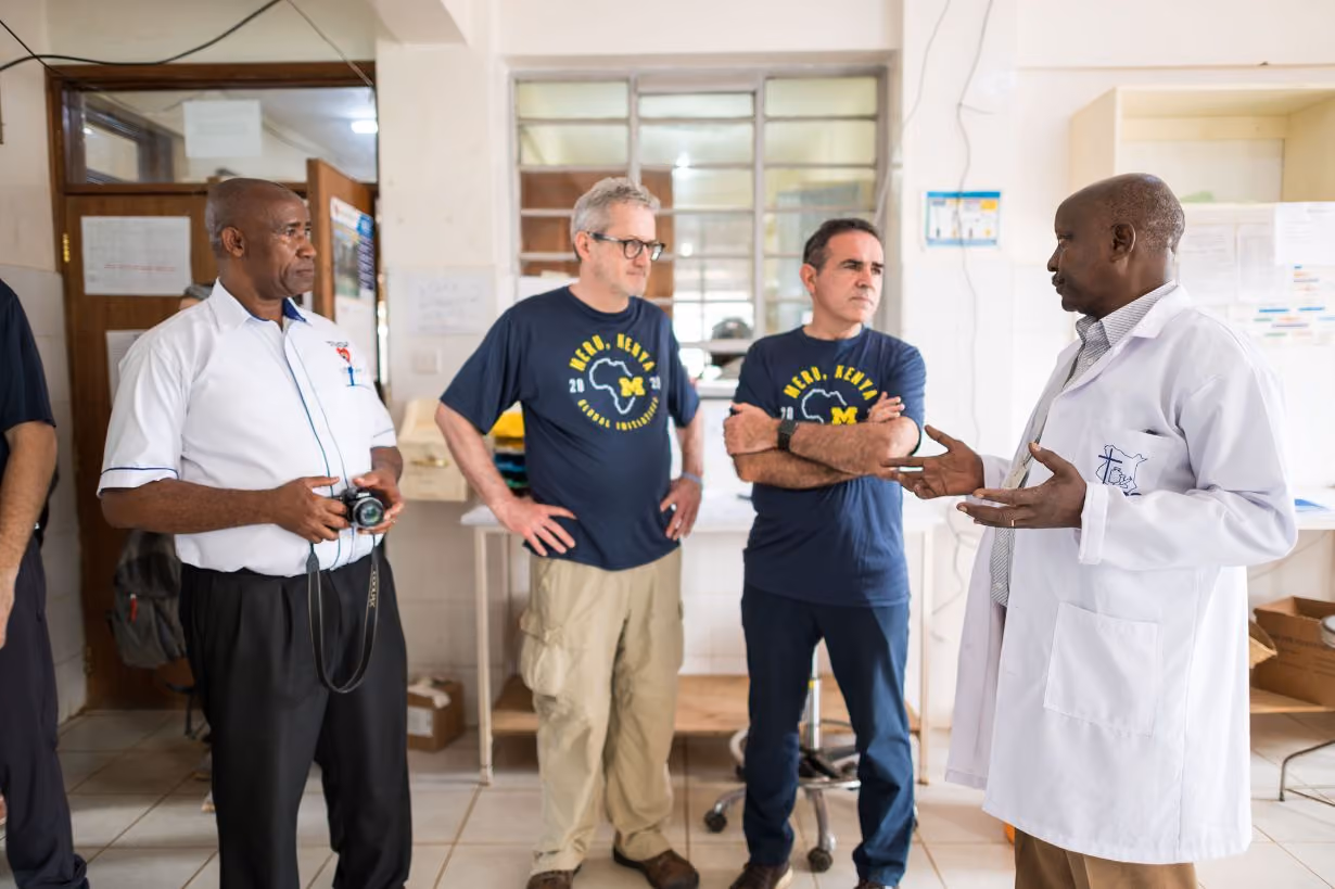 Two University of Michigan Center for Global Health Equity researchers talking with two Kenyan scientists