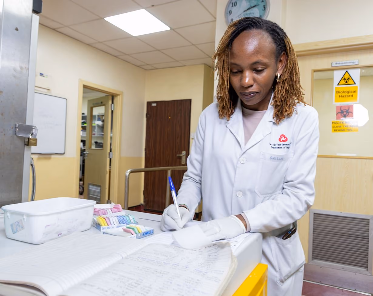 Female cancer researcher writing notes in Kenya for CRC AI project photo by Dann Mchoraji