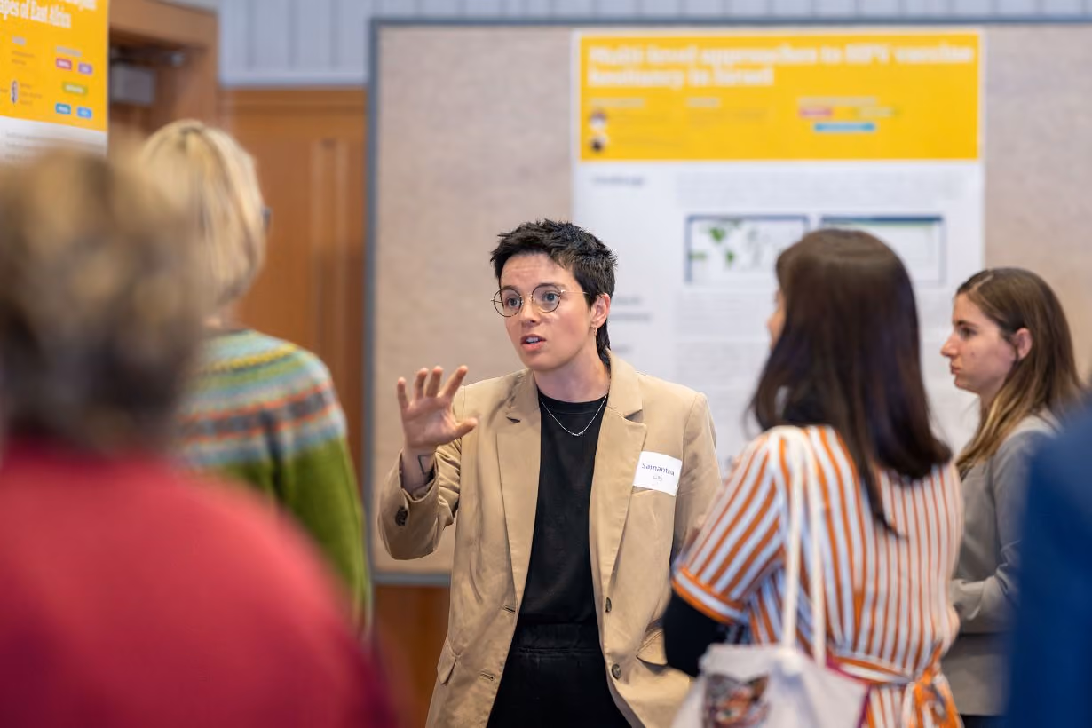 Student sharing their research work in front of poster at Center for Global Health Equity's annual community gathering event at the University of Michigan