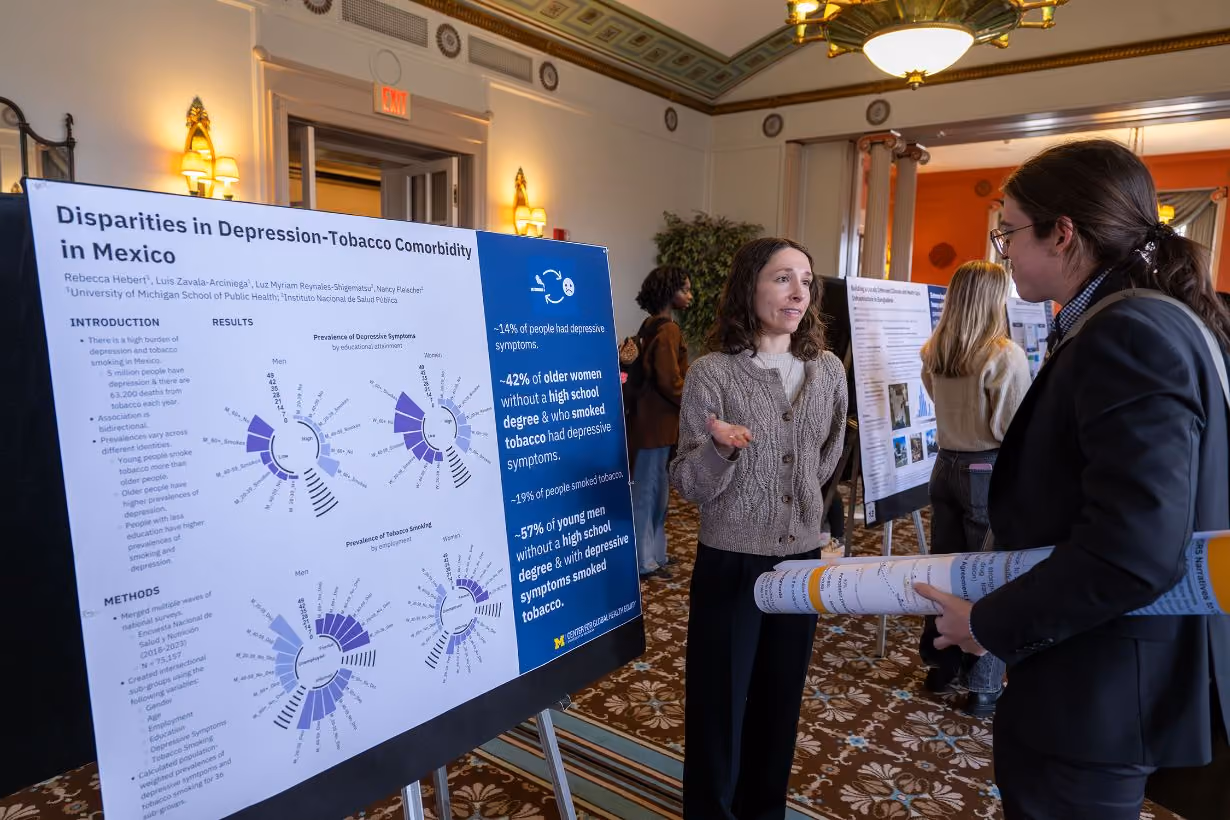 Impact scholar sharing disparities in depression-tobacco comorbidity in Mexico research work in front of poster at Center for Global Health Equity's annual community gathering event at the University of Michigan