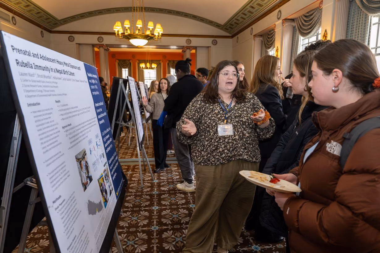 Impact scholar sharing prenatal and adolescent rubella in Nepal research work in front of poster at Center for Global Health Equity's annual community gathering event at the University of Michigan