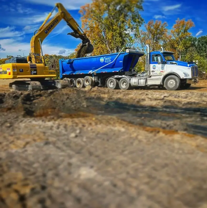 excavator dumping dirt into truck
