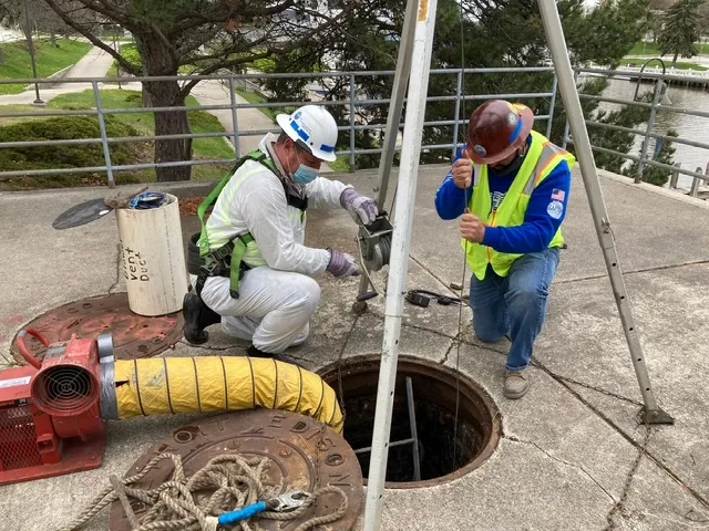 workers cleaning industrial tanks at top of tank