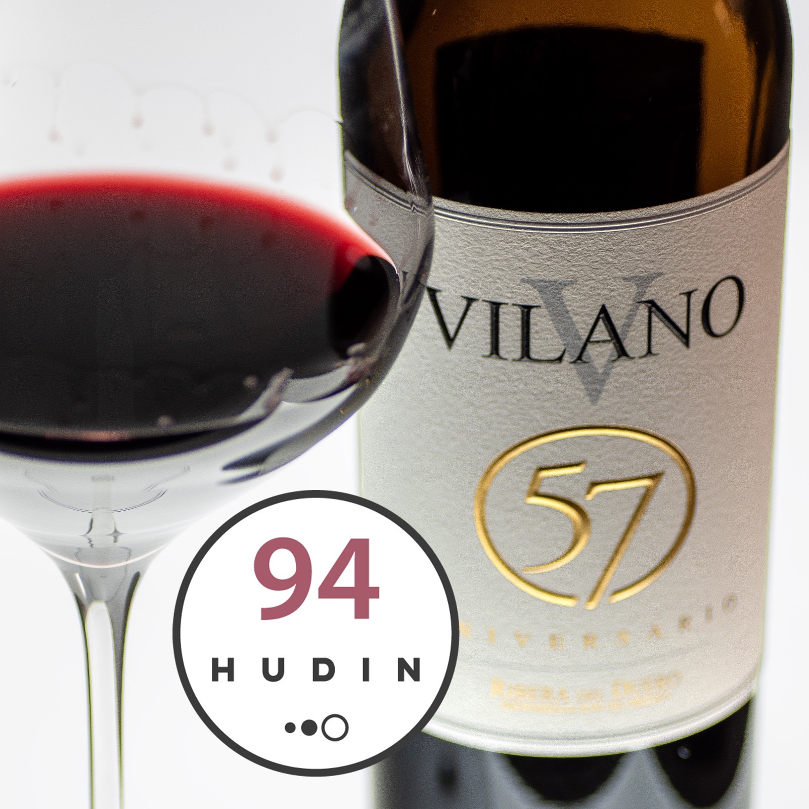 Botella de Vilano 57 Aniversario y copa de vino tinto junto al sello de 94 puntos de Miquel Hudin