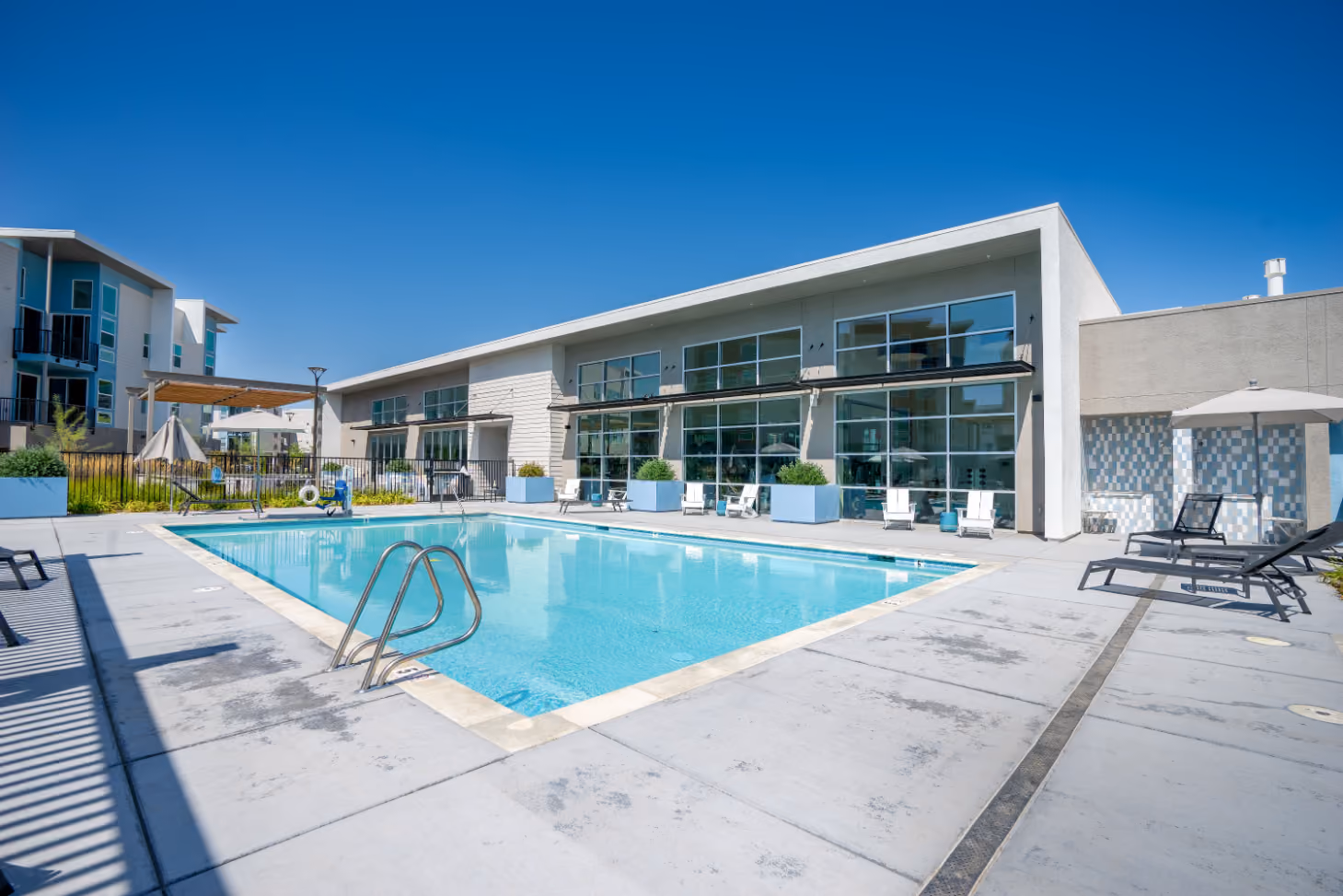 Outdoor pool with lounge chairs alongside the fitness center building