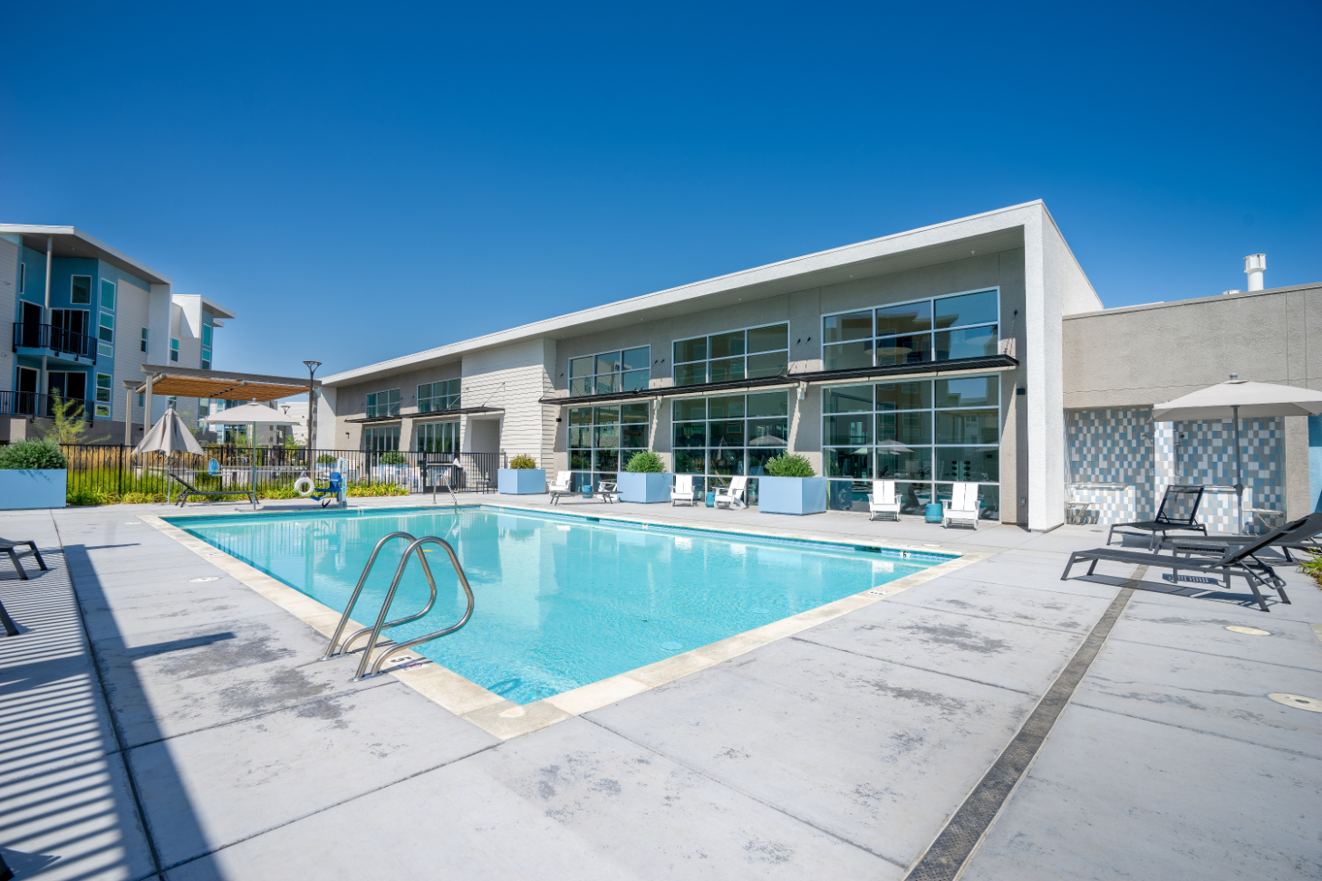 Outdoor pool with lounge chairs alongside the fitness center building