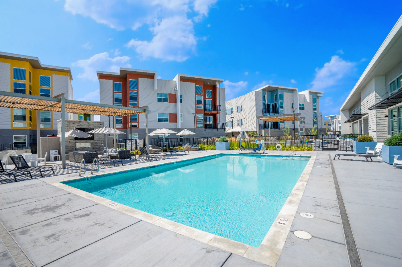 Outdoor pool with lounge chairs alongside the fitness center building