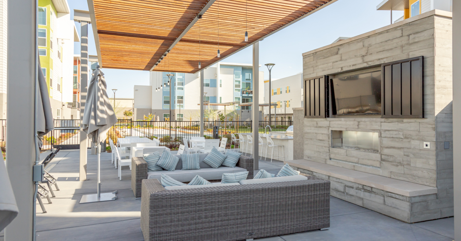 Outdoor lounge with fireplace and wall-mounted TV