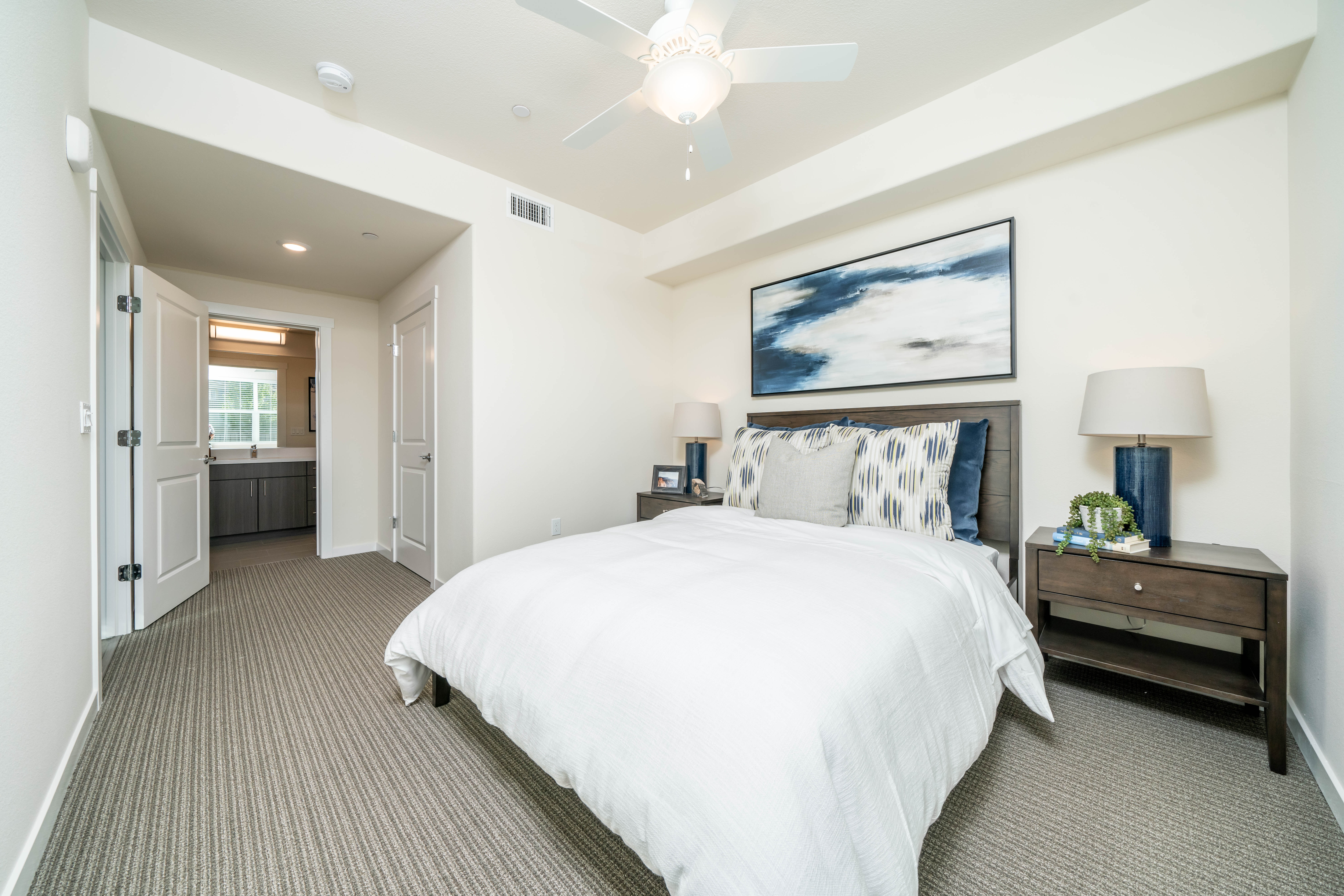 Bedroom with bed, bedside table with lamps, and wall art