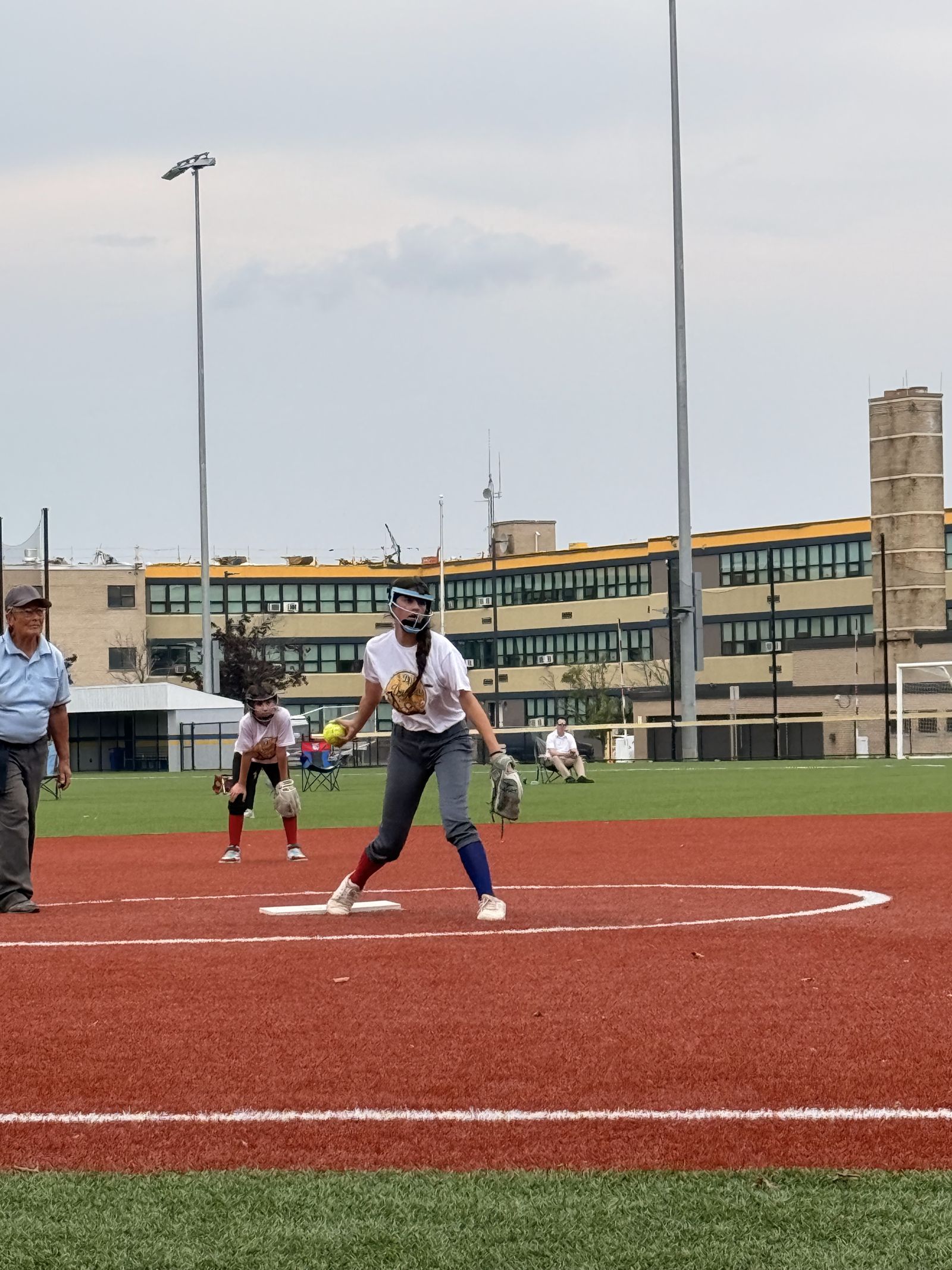 A pitcher winds up in front of the scoreboard.
