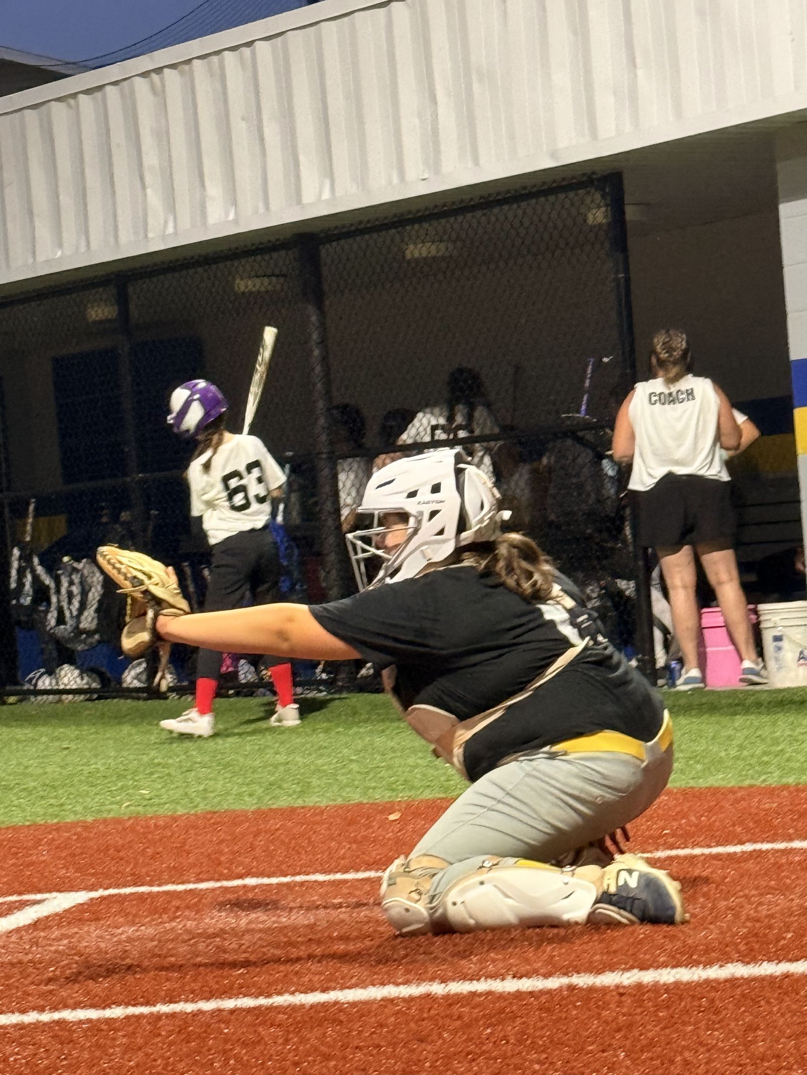 A catcher on one knee in full gear.