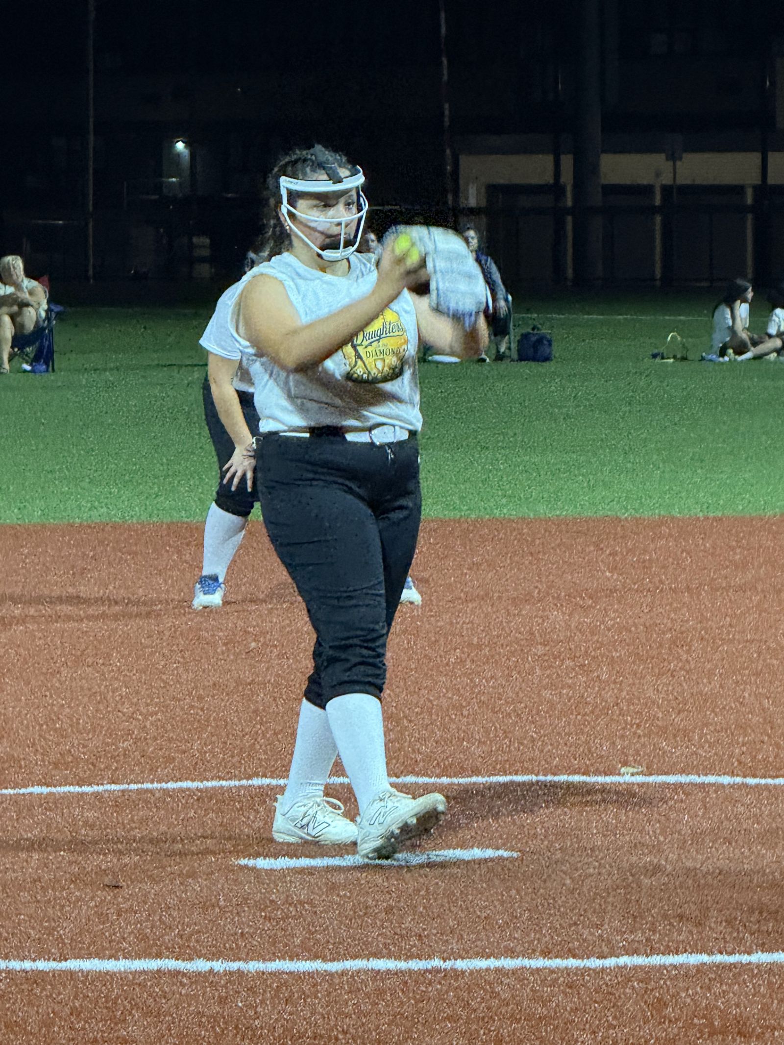 A pitcher mid-windup under the lights.