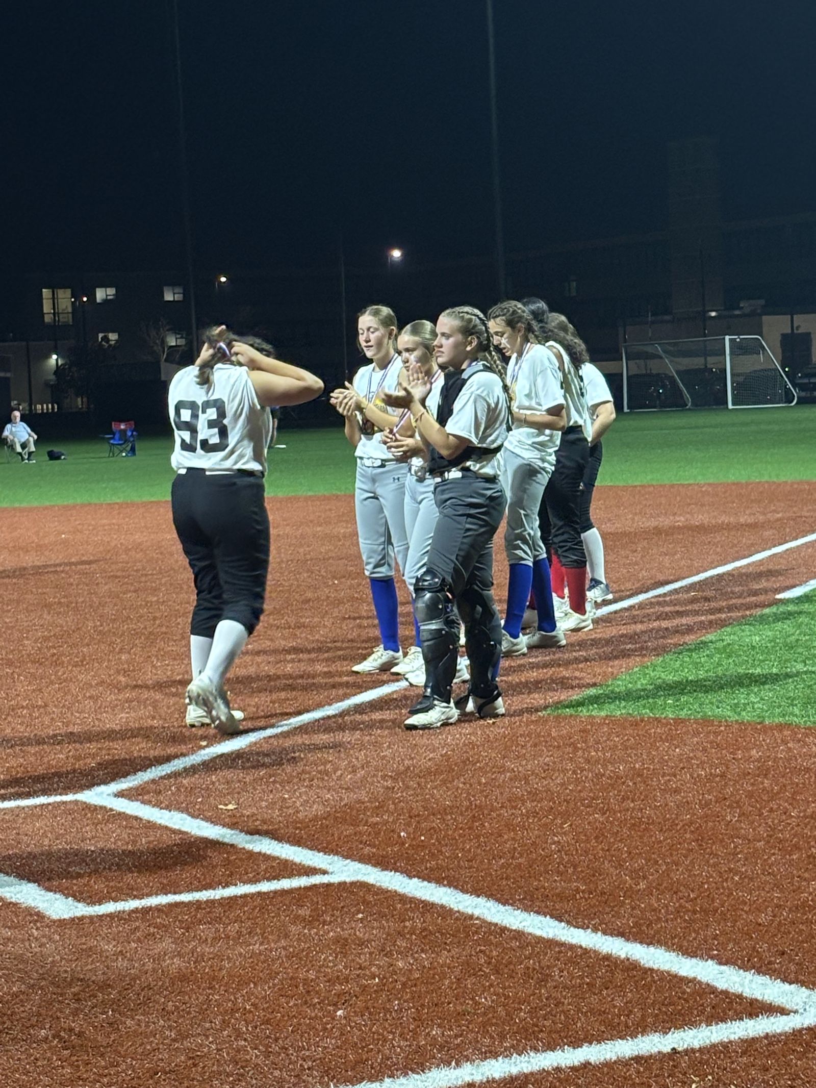 Teammates line up on the baseline under the lights.