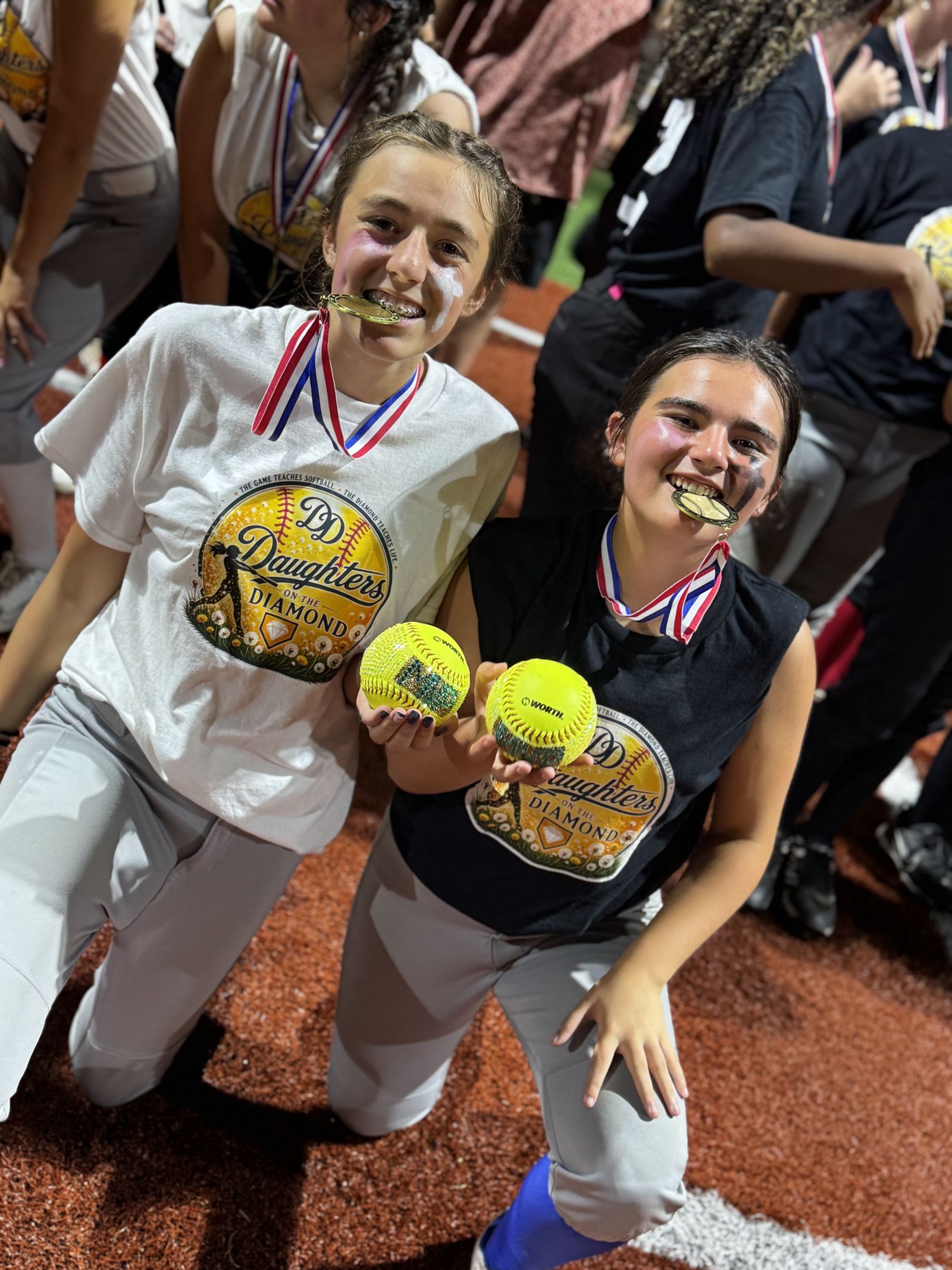 Two players show off their gold softballs and medals.