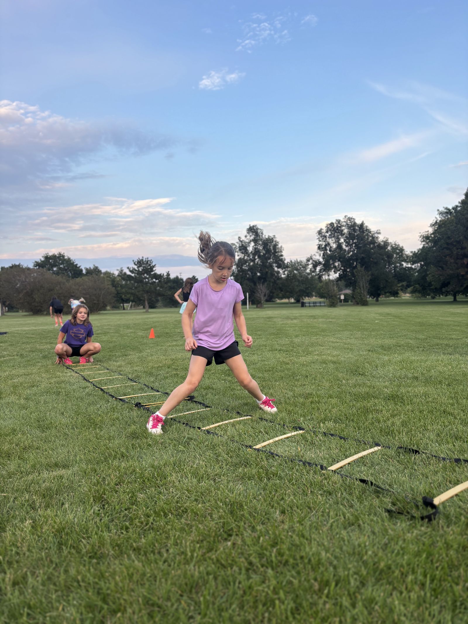 A player works the ladder while a coach watches.