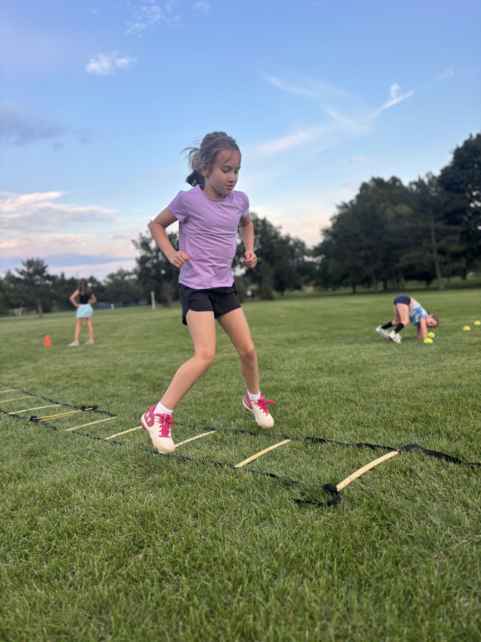 A player mid-hop through the agility ladder at golden hour.