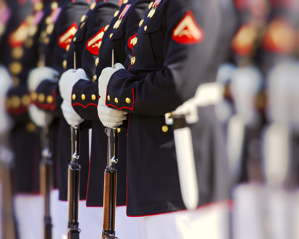 Uniformed soldiers in formation, holding rifles vertically in front of them.