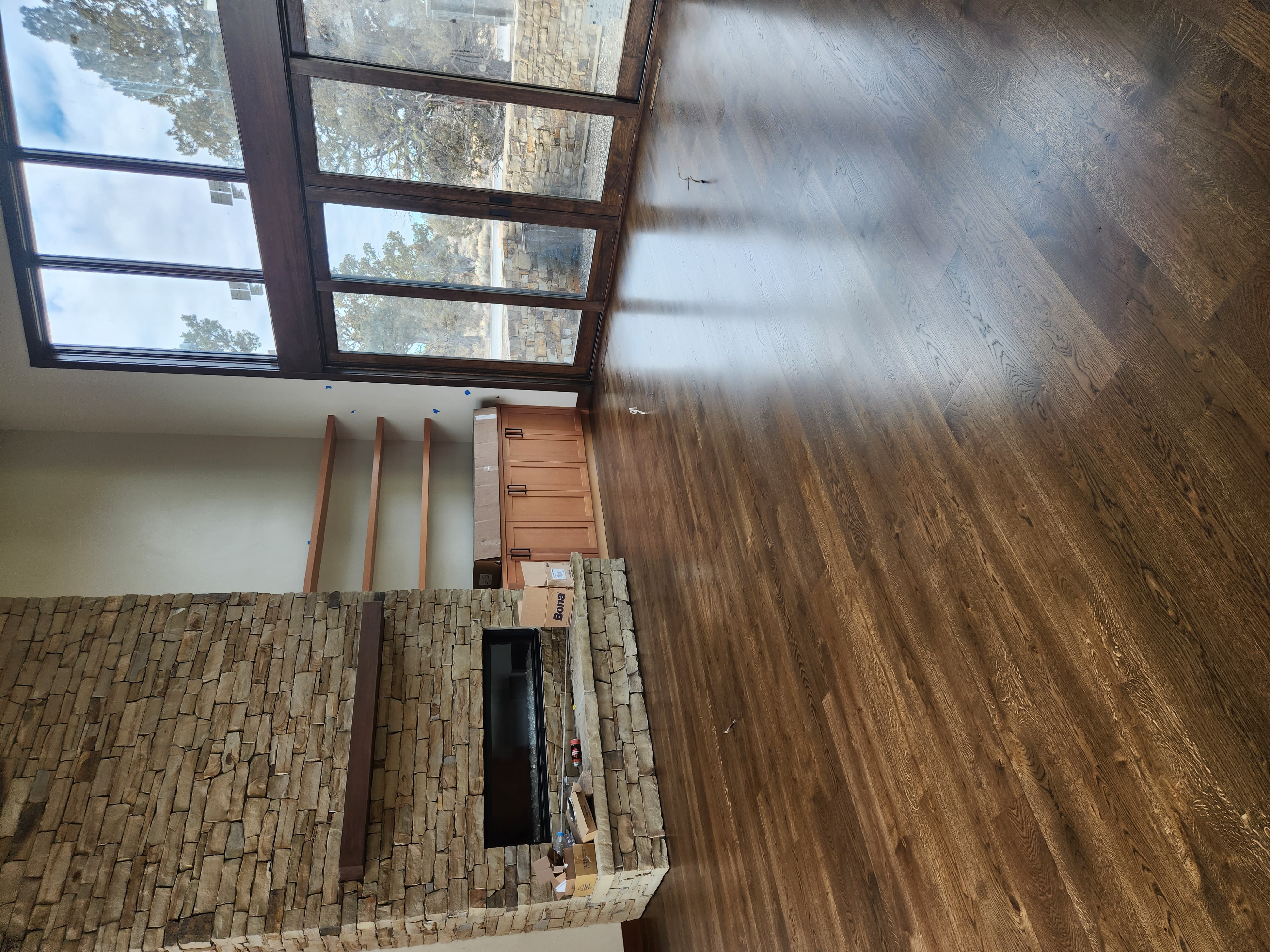 Room with polished wooden floor, stone fireplace, built-in shelves, and large glass sliding doors.