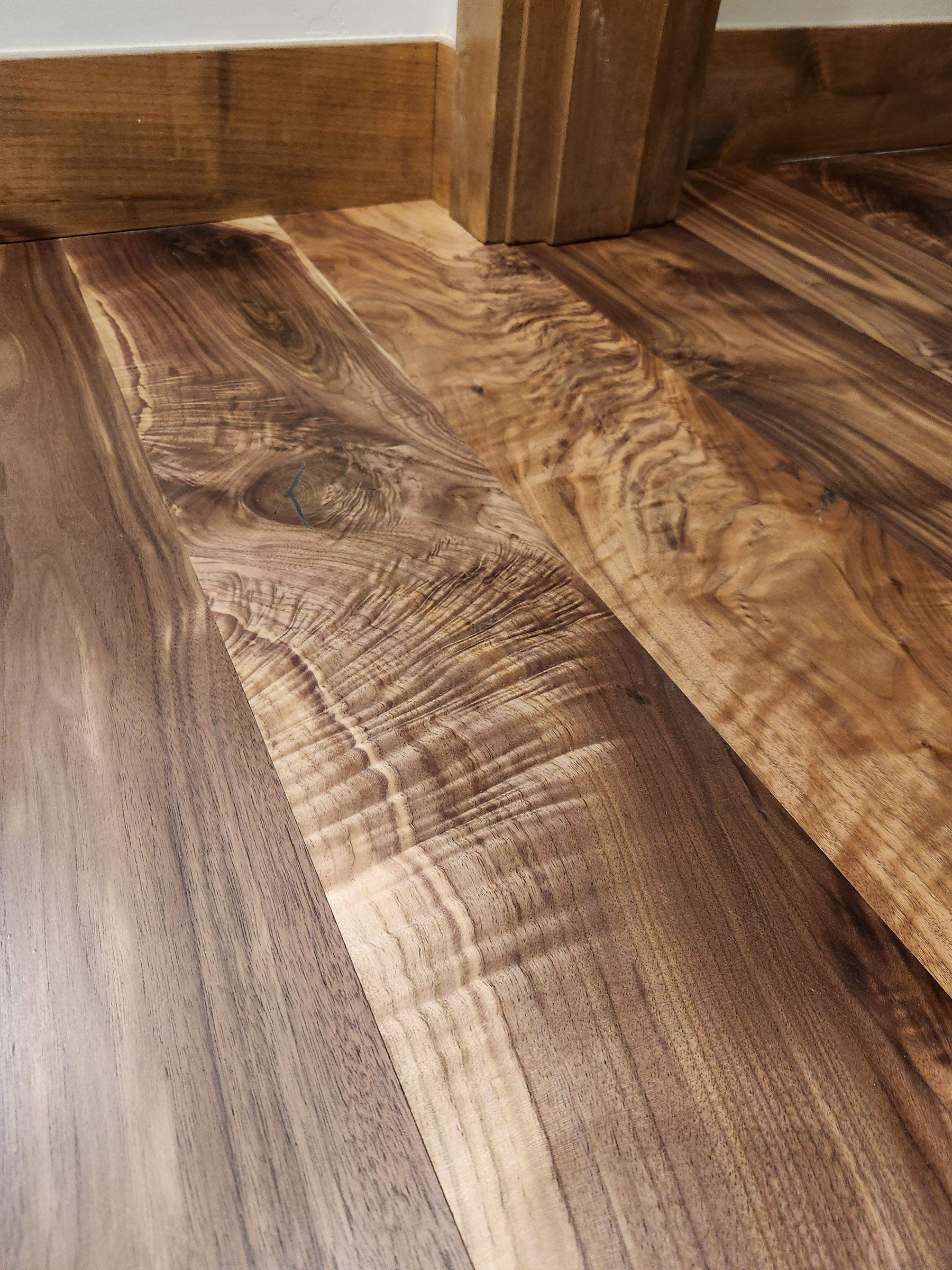 Close-up of smooth wooden floorboards with varied natural grain patterns and colors near a baseboard.