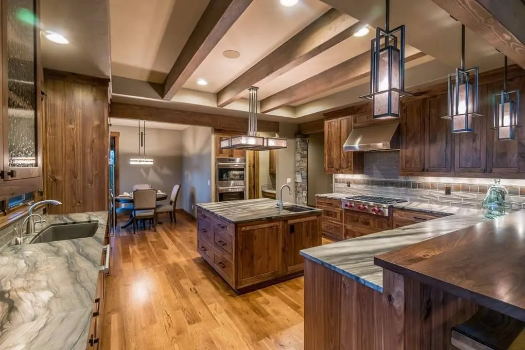 Spacious kitchen with wood cabinets, marble countertops, island, hardwood floor, and modern pendant lights.