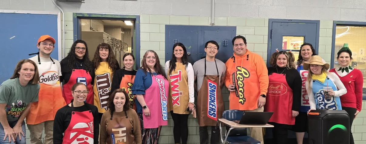Staff dressed as Halloween candy costumes posing together indoors
