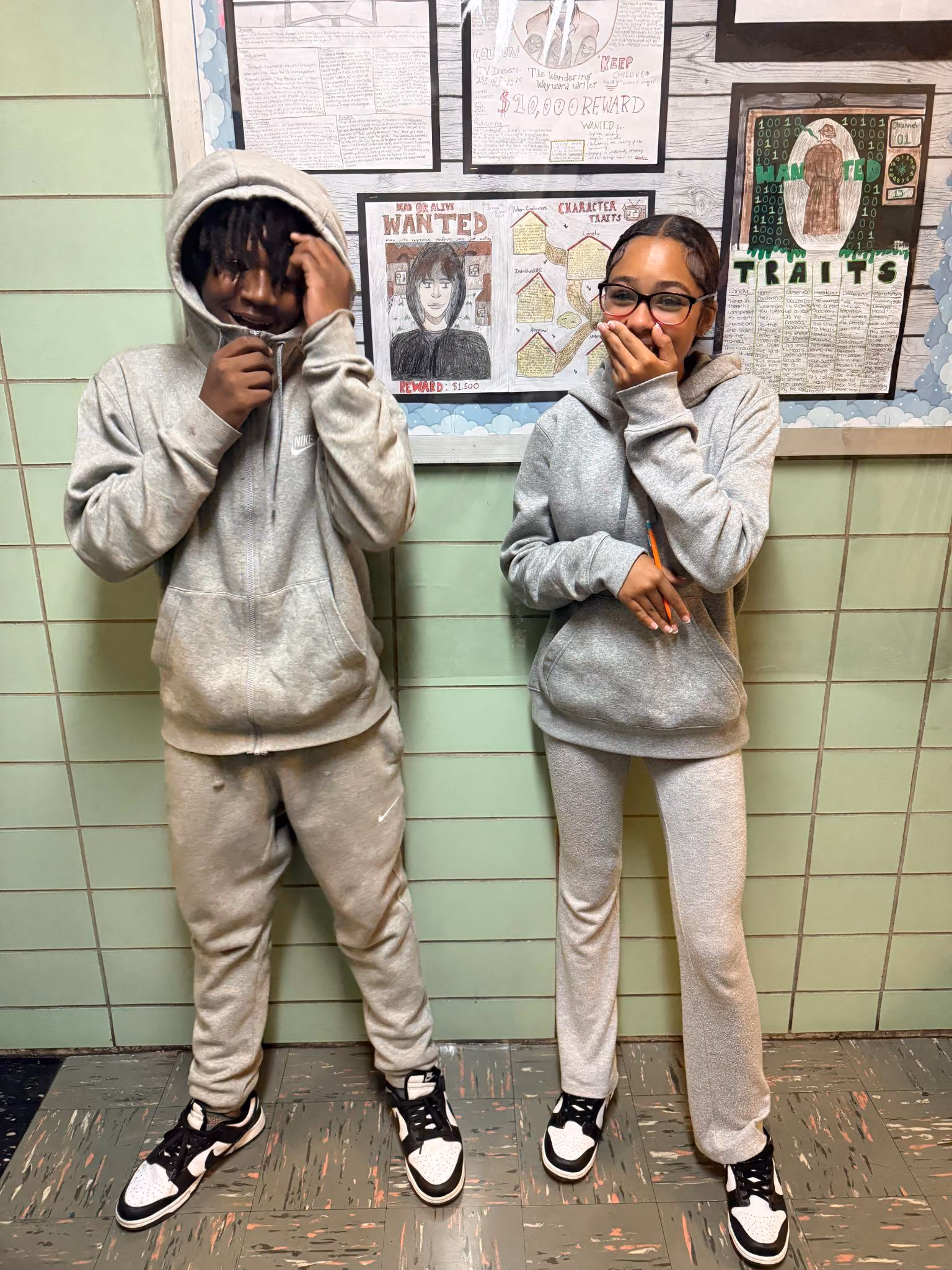 Two students posing in front of character traits classroom wall display