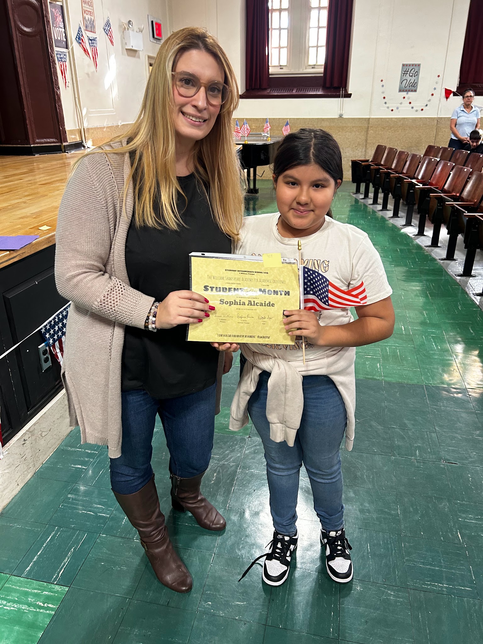 Student Sophia Alcaide receives Student of the Month certificate from teacher