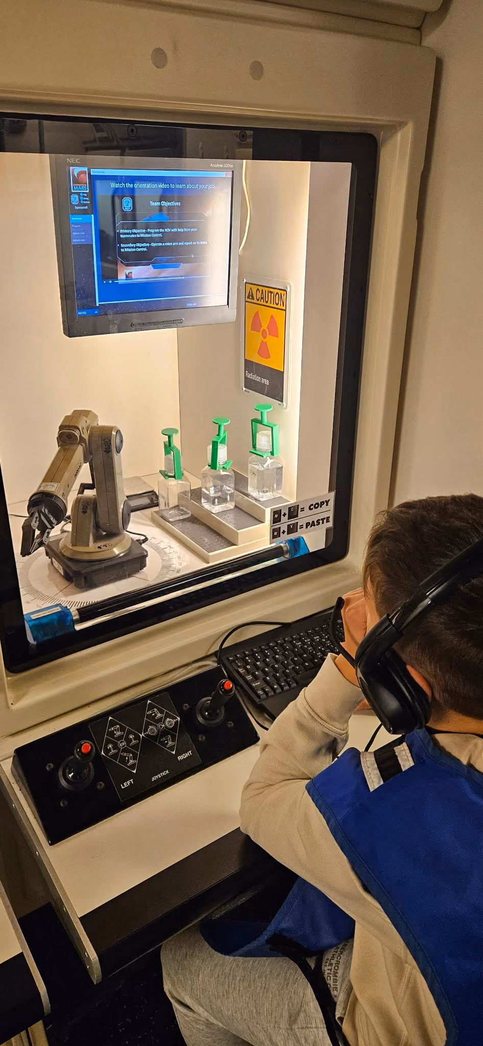 Student operating robotic arm controls at a science exhibit