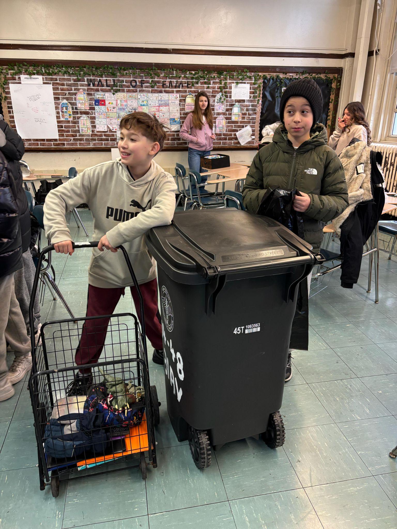 Students collecting donations with cart and bin in classroom