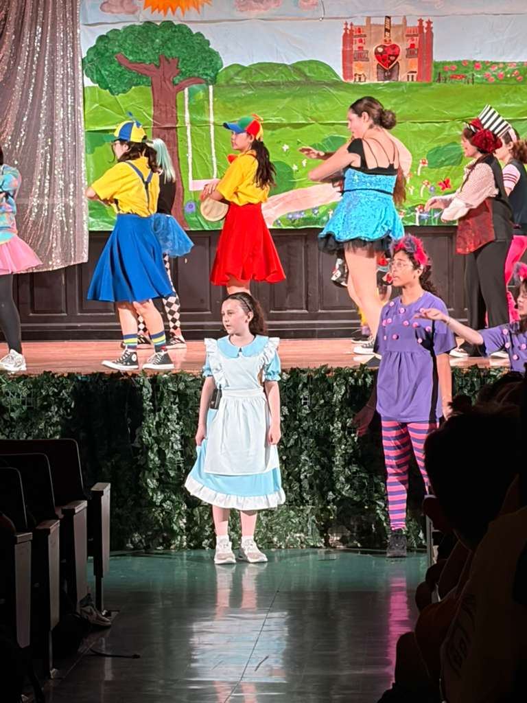 Students performing Alice in Wonderland school play on stage