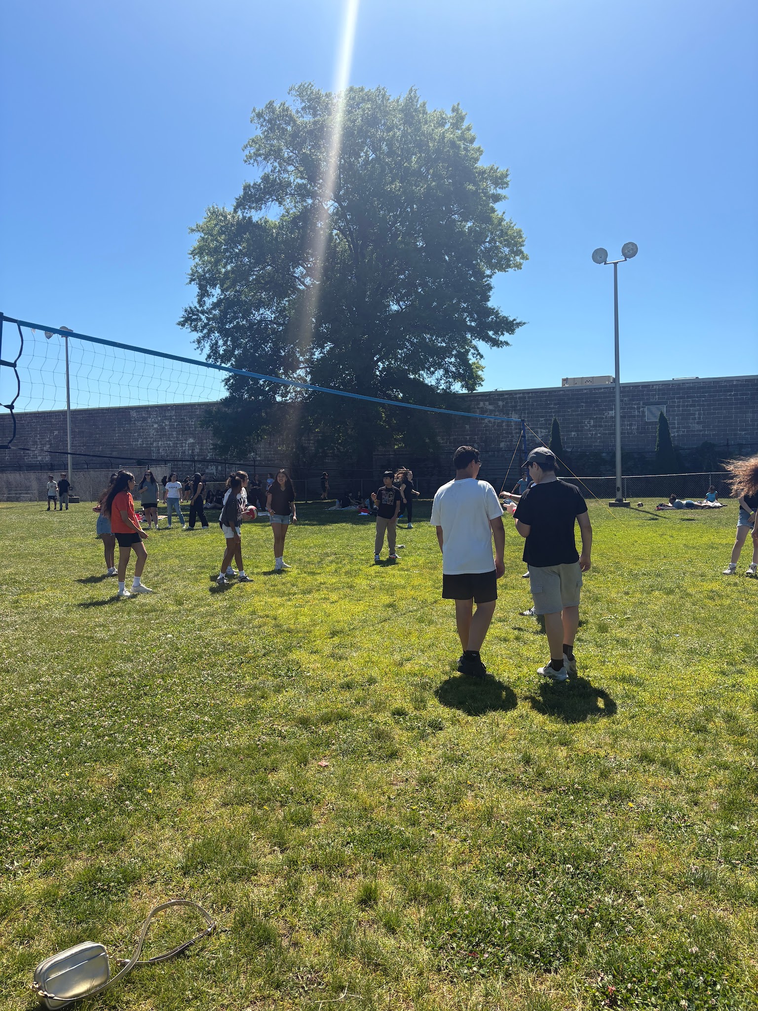 Students playing volleyball outdoors on a sunny school field