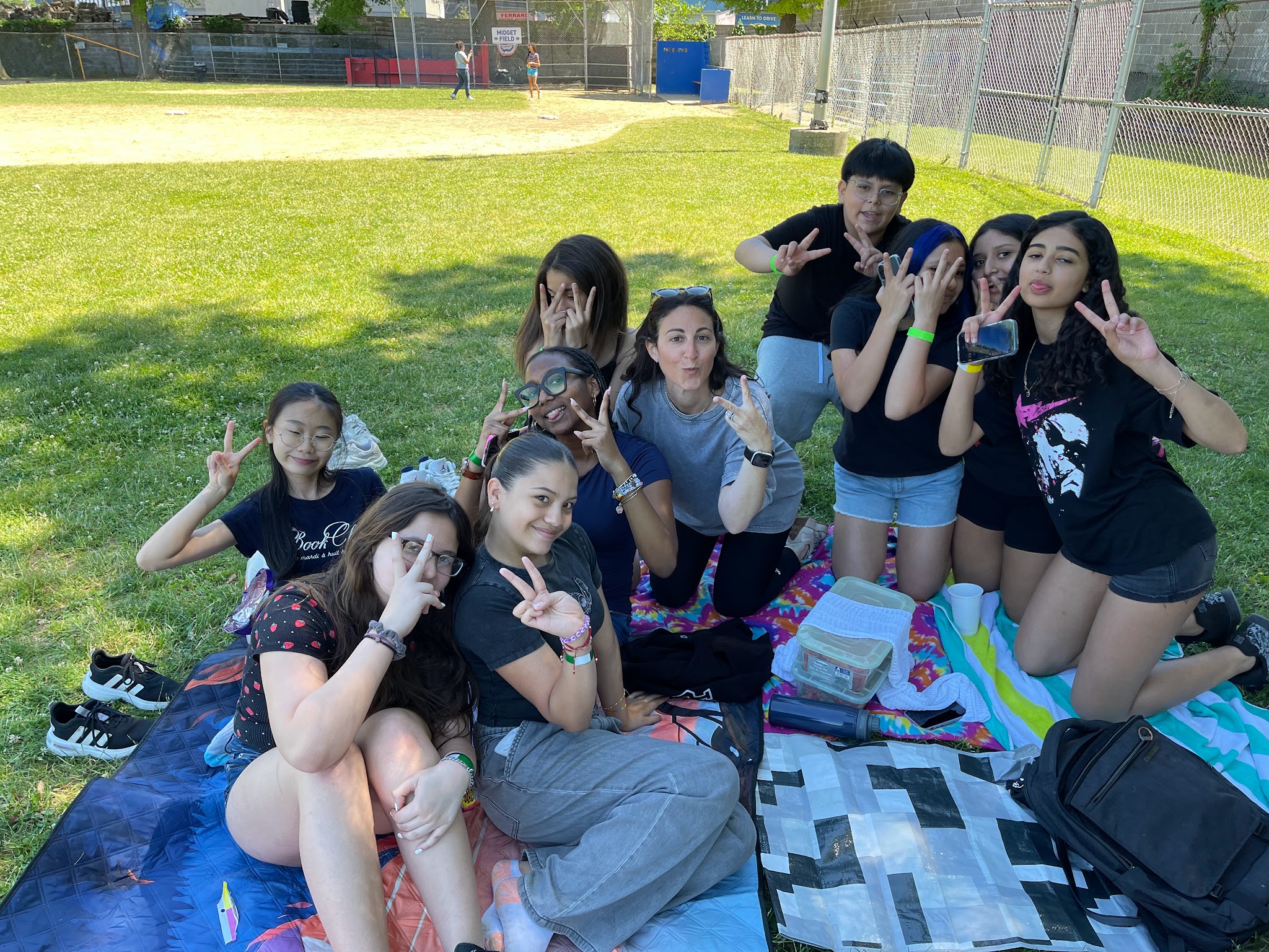 Students and teacher posing with peace signs at outdoor picnic