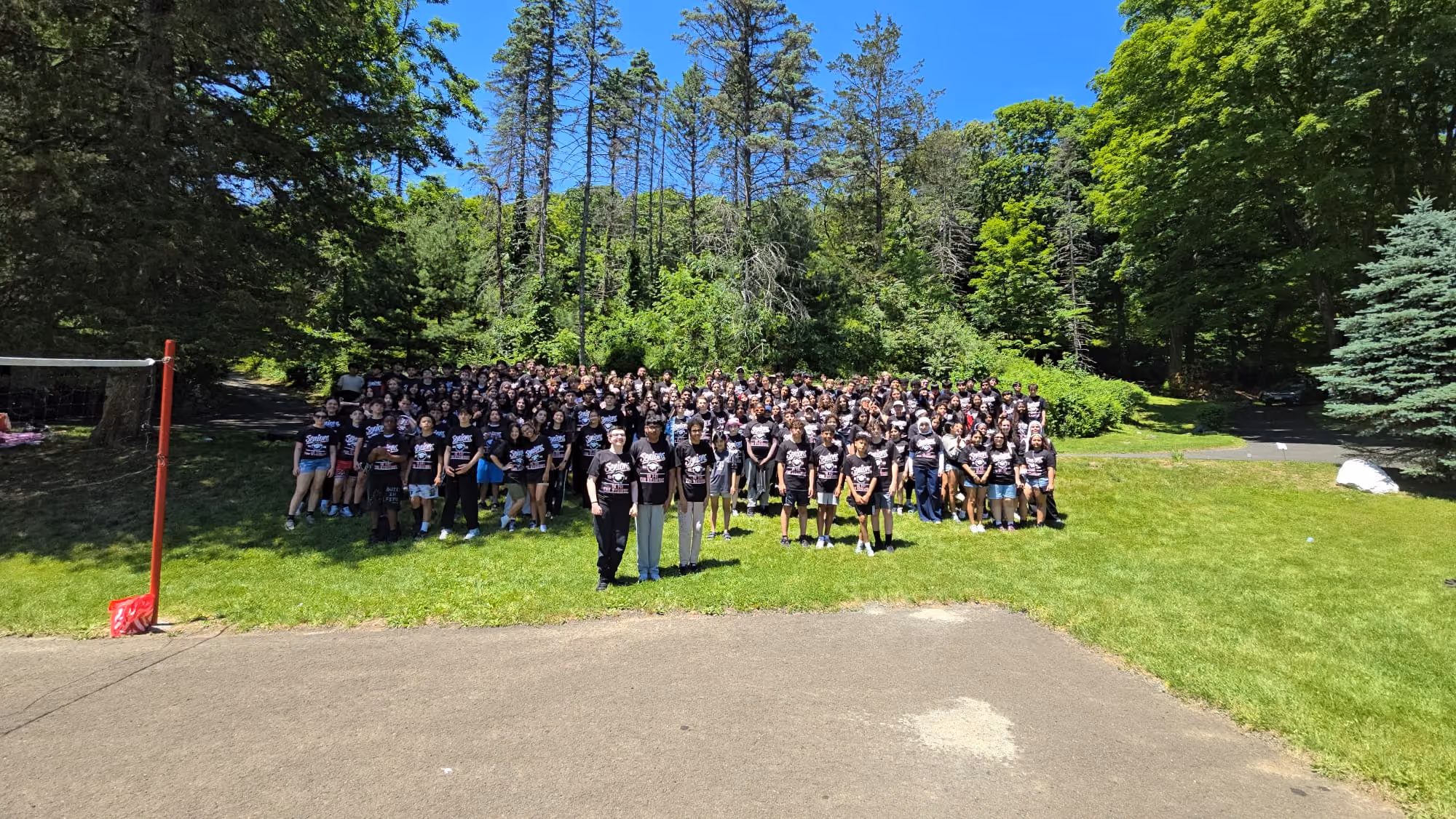 Large group of students in matching black shirts posing outdoors
