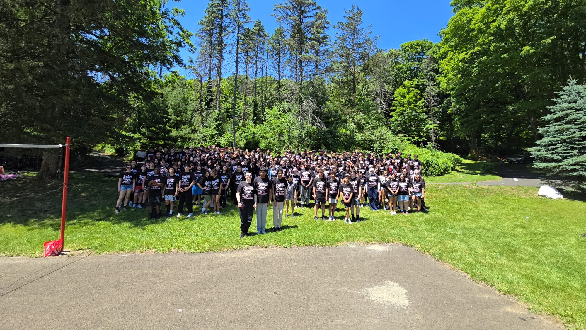 Large group of students in matching black shirts posing outdoors